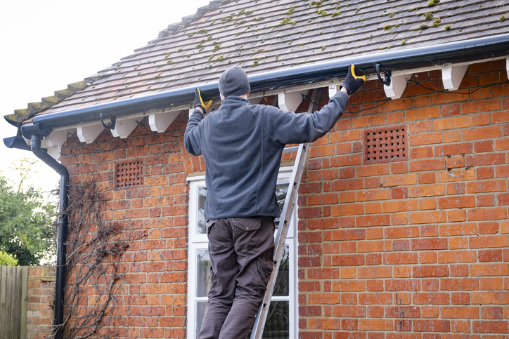 Dublin roofer fixing a gutter on the side of a house.