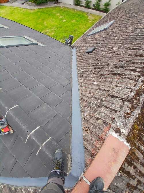 image of a roofer looking down on a slate roof being repaired in Dublin.
