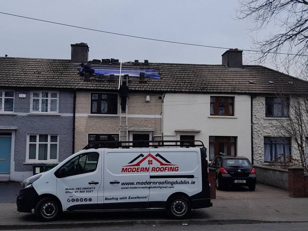 Image of a roofer working on a roof in Dublin with a van parked in front of the house.