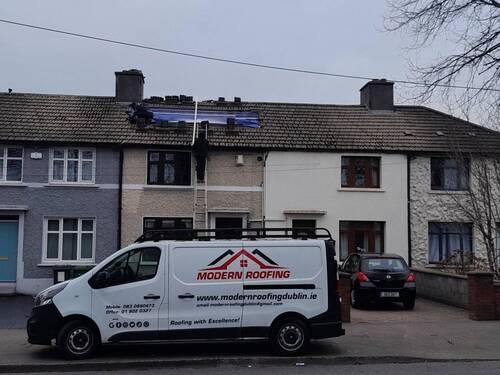 Image of a roofer working on a roof in Dublin with a van parked in front of the house.