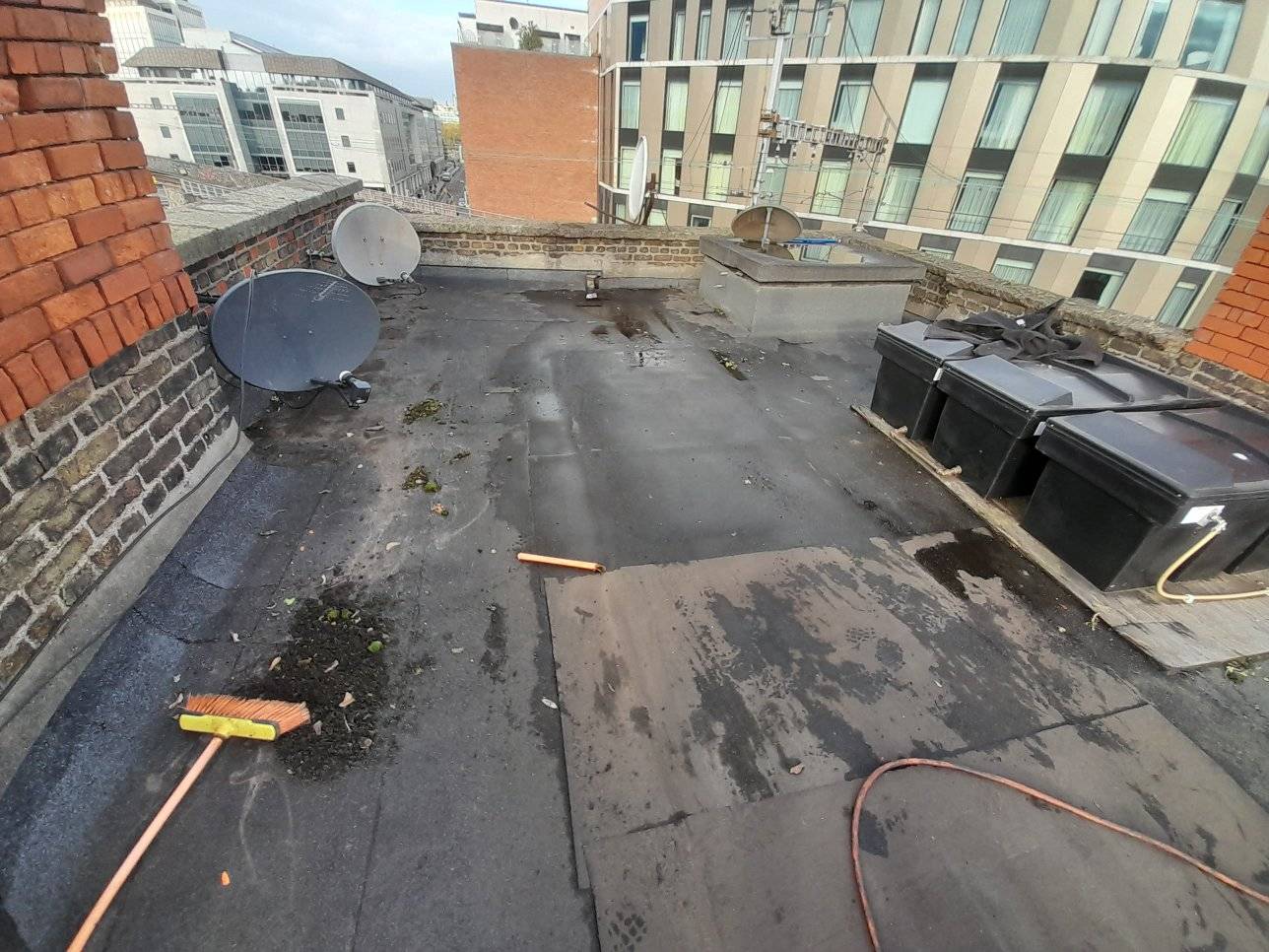 a flat roof in Dubin with leaking roof felt satellite dishes and water ank on top of it.