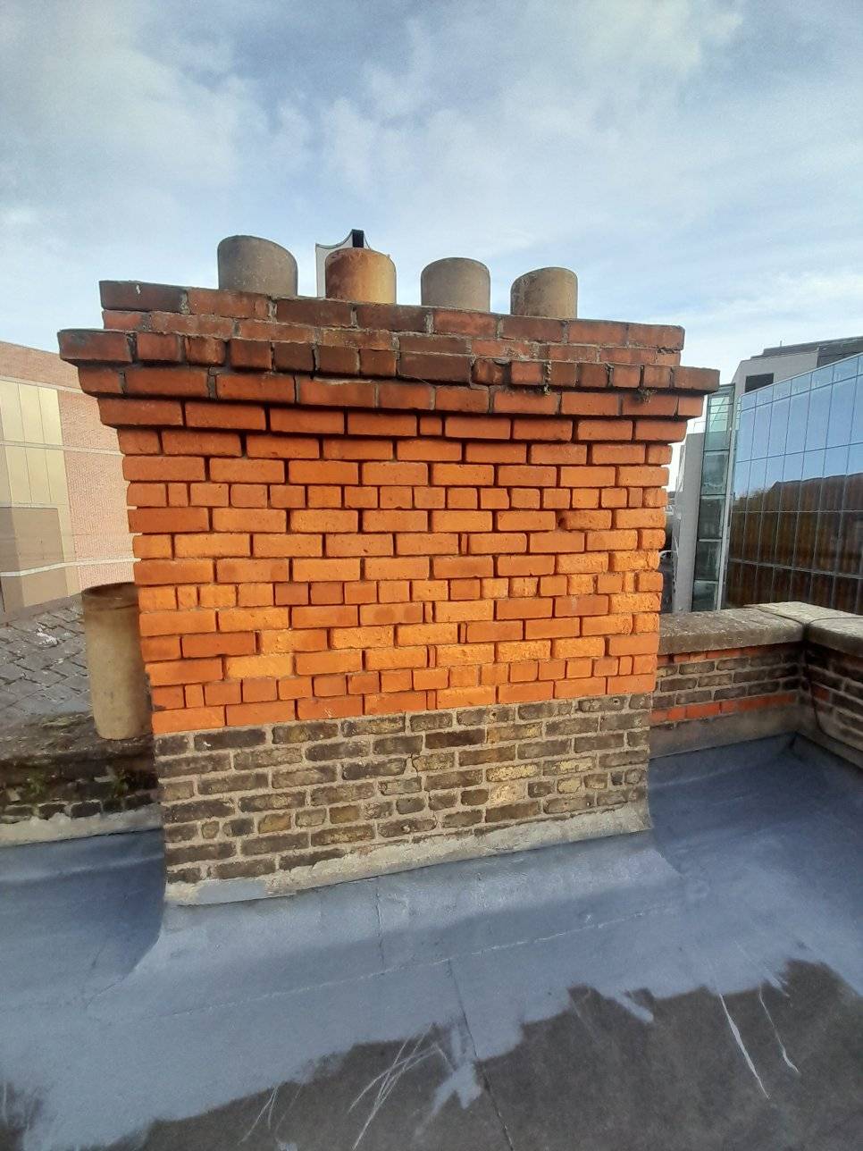 a red brick chimney on the flat roof with rubber seal around the bottom of the chimney