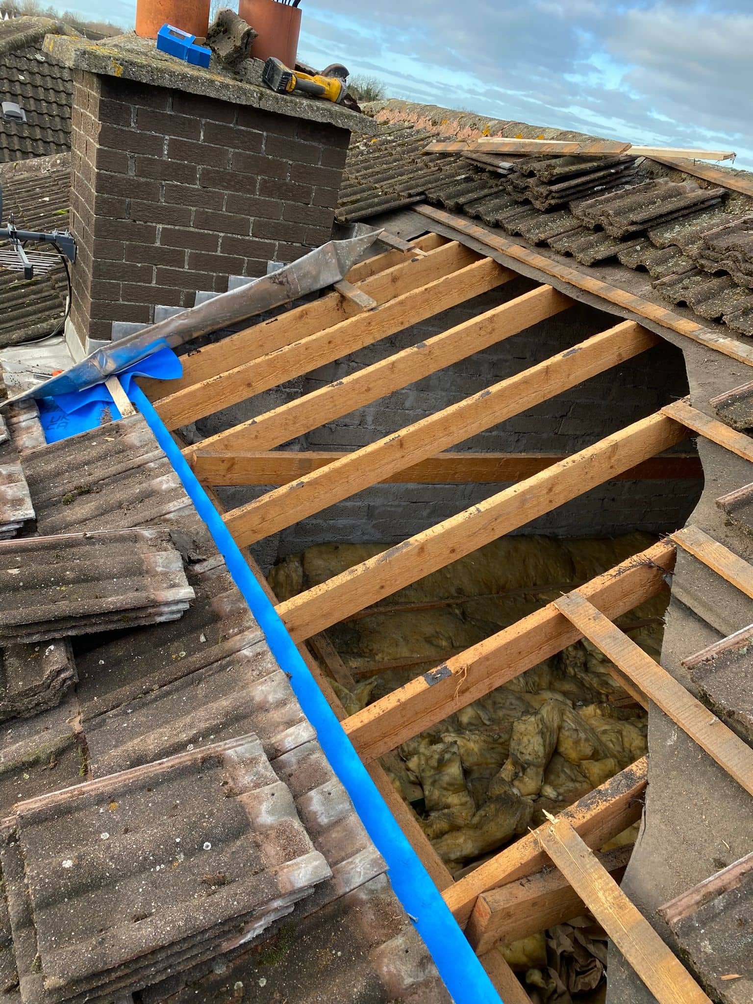 Roof tiles removed and the membrane also removed revealing the wood struts and the attic inside.