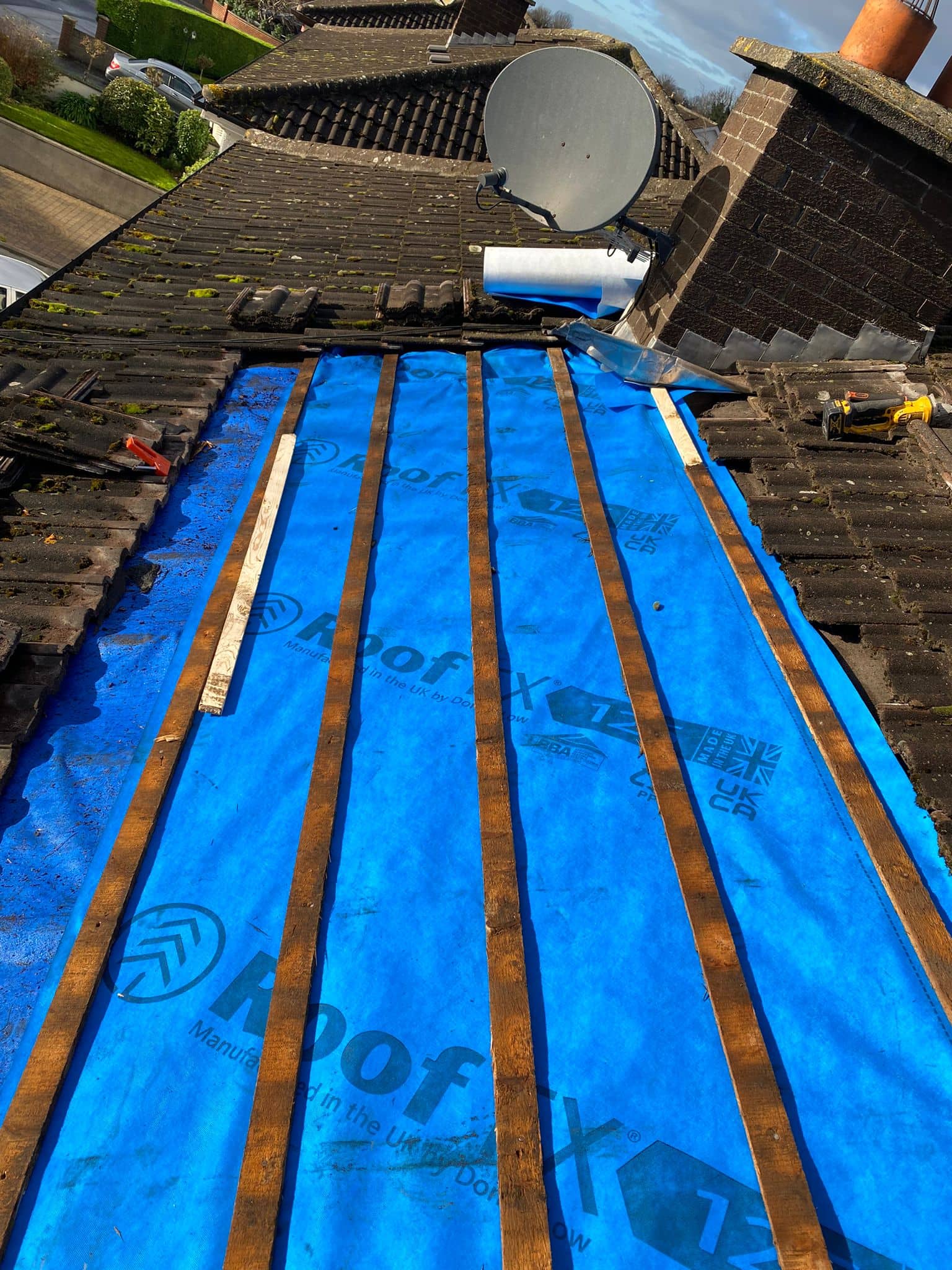 Roof tiles removed on a roof in Dublin and the blue coloured membrane visible underneath.