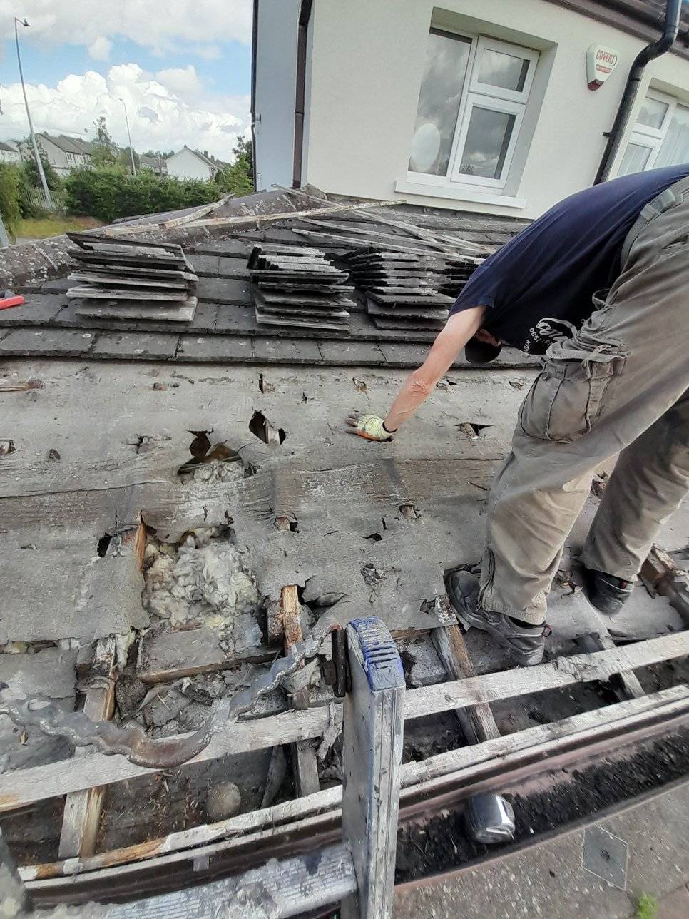 Roof with tiles removed exposing damage underneath.