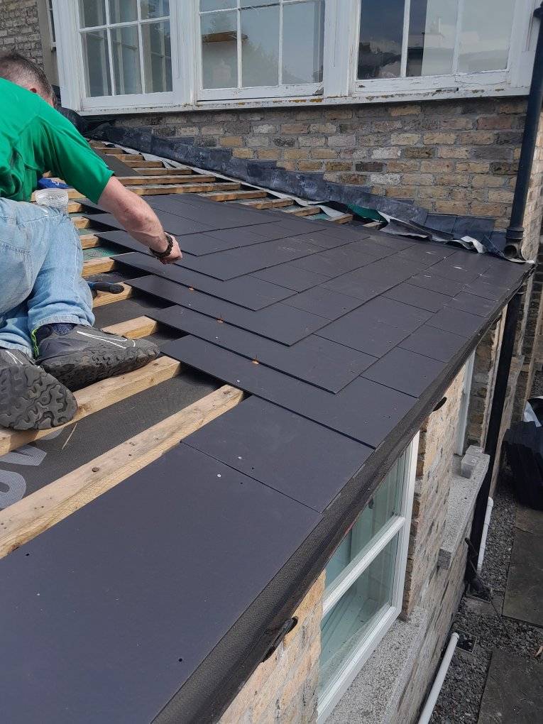 Slate roof replacement with new tiles being added to the roof