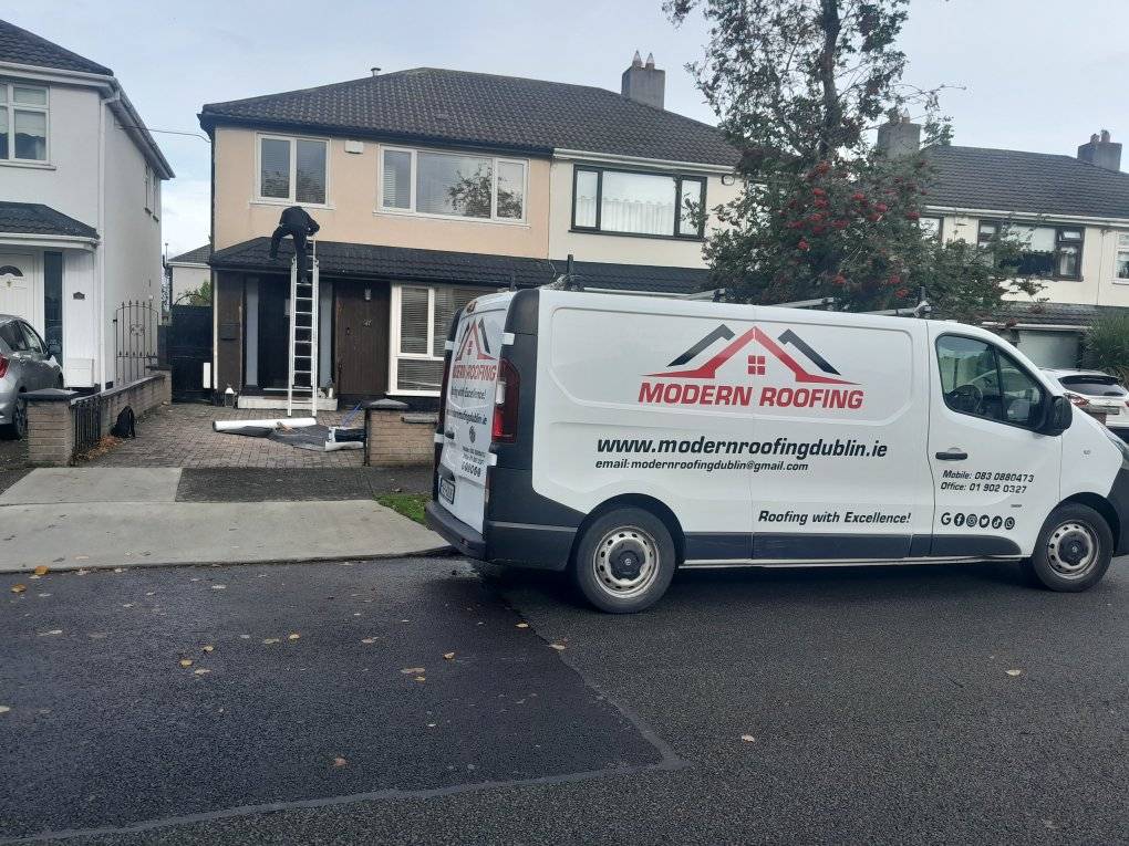 Modern Roofing Dublin van parked outside a house and a roofer up on a ladder inspecting storm damage.